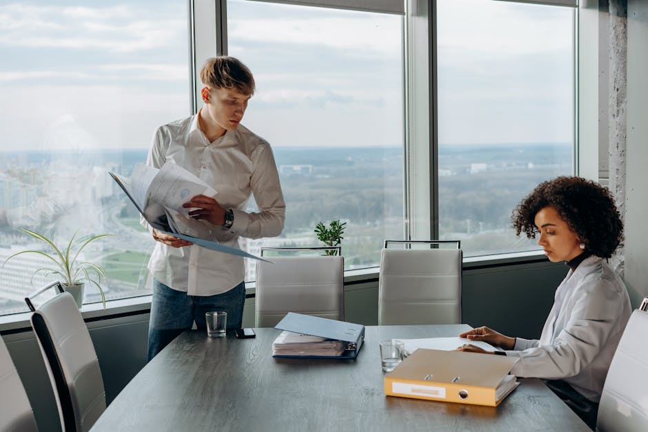 Business professionals reviewing documents in a bright, modern office setting with a city view.