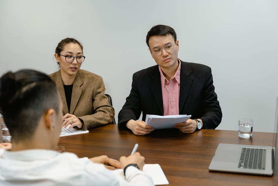 Colleagues engaged in a business meeting, discussing documents in an office setting.